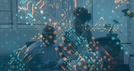 Collaborating tech professional and partner viewing laptop in home workspace, with circuit overlay