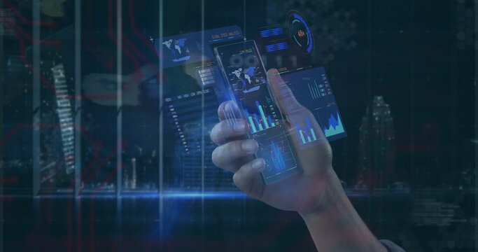 Gripping human hand projecting holographic charts above urban night skyline, with smartphone panels