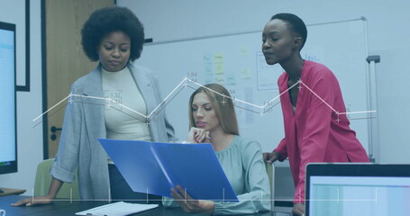 Leaning three colleagues wearing blazers reviewing report in conference room, with blue folder