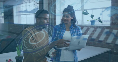Discussing project two colleagues collaborating in office loft, with laptop and coffee mug