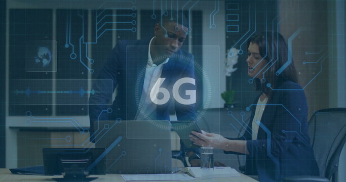 Discussing colleagues in suit and blazer examining laptop smartphone in office with 6G overlay