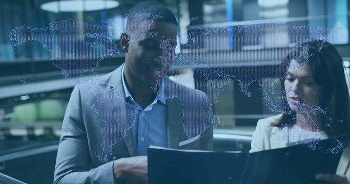Professionals in business attire reviewing black folder in lobby, with digital world map overlay