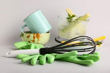 Many dirty dishes with cutlery and rubber gloves on grey background
