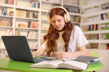 Student with laptop studying at table in library