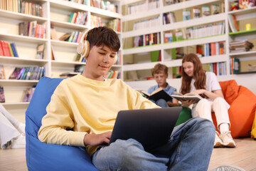 Student with laptop studying on bean bag in library