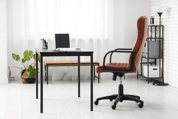 Interior of modern office with workplace, lamp and shelf unit