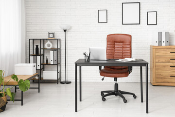 Interior of modern office with workplace, lamp and shelf unit