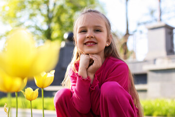 Cute little girl near beautiful yellow tulips outdoors