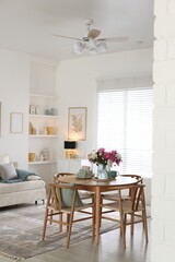 Dining table with beautiful flowers and dishware in room, space for text. Interior design