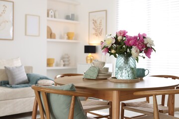 Dining table with beautiful flowers and dishware in room, space for text. Interior design