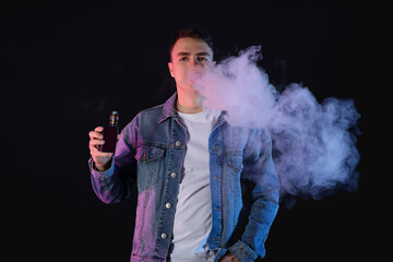 Young man smoking electronic cigarette on black background