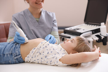Sonographer conducting little girl's abdominal ultrasound examination in clinic, closeup