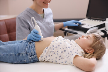 Sonographer conducting little girl's abdominal ultrasound examination in clinic, closeup