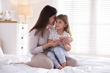 Mother and daughter on bed at home