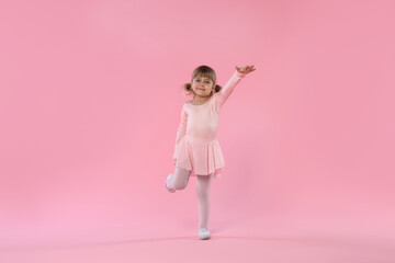 Cute little girl dancing on pink background