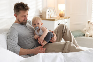 Bedtime. Happy father with his cute little baby on bed at home