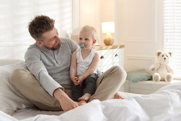 Bedtime. Happy father with his cute little baby on bed at home