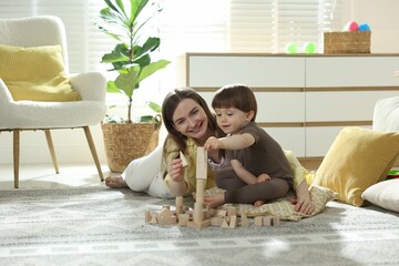 Mother and son playing with wooden building blocks at home