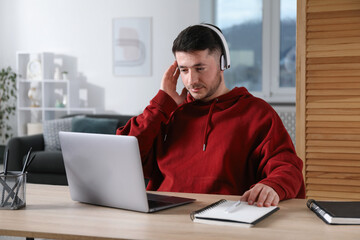 Man learning online using laptop at desk indoors. Self-study