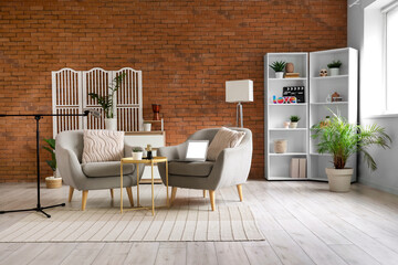 Interior of podcaster's studio with armchairs, folding screen and shelf unit