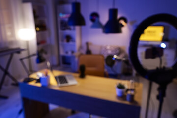 Blurred view of podcaster's workplace with glowing lamps in dark studio