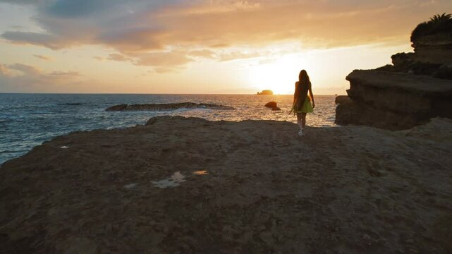 Woman walking at sunset on the edge of a rocky coastline in Kefalonia Greece