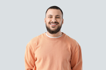 Young man with beautiful smile on light background