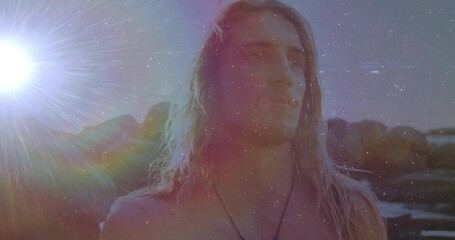 Health fitness model with pendant standing by rocky shoreline under grainy sun flare, turning away - Powered by Adobe