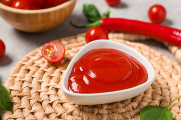 Bowl of tasty ketchup with basil leaves and cherry tomatoes on grey background, closeup