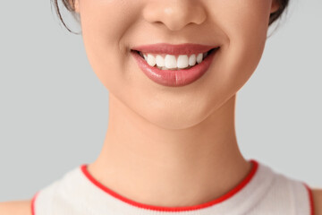 Smiling young woman on light background, closeup