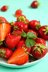 Plate with fresh ripe strawberries on turquoise background, closeup