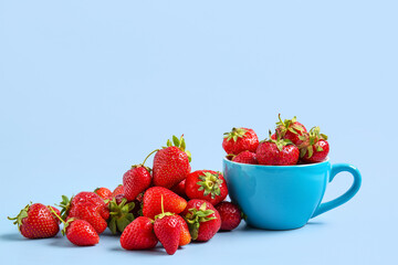 Cup with fresh ripe strawberries on blue background