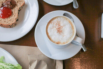 Hot coffee latte cappuccino with milk foam on wooden table for morning breakfast. Refreshing drink.