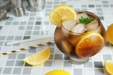 Glass of Long Island iced tea cocktail with mint on grey tile background