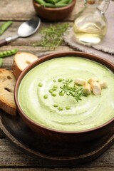 Tasty pea cream soup with croutons and thyme served on wooden table, closeup