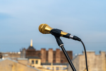 A golden microphone mounted on a stand, set against a backdrop of an urban skyline. the scene combines elements of performance and city life, capturing a moment of potential creativity.