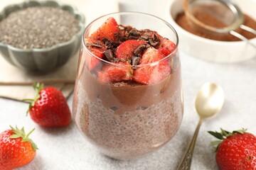Delicious chocolate pudding with chia seeds and strawberries on light grey table, closeup