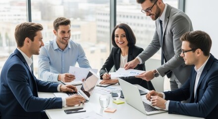 Diverse group of business professionals collaborating in a modern office meeting discussing reports and data on laptops and papers with bright natural light