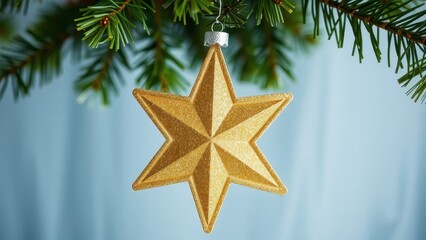 Golden star ornament hangs from a green christmas tree branch against a blue background