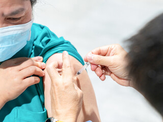 An elderly woman worker is getting vaccinated against influenza.