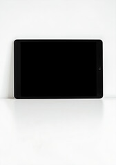 Tablet Laying Flat at Top of White Surface - Digital tablet with black screen placed near the top edge of a white surface, leaving bottom space clean