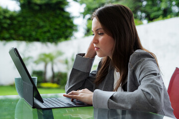 Young woman working remotely with tablet and smartphone outdoors