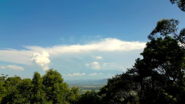 Lifting above the trees to reveal the green valley below and the storms clouds brewing above the mountains.
