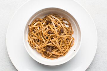 Overhead view of mongolian ground beef noodles in a white bowl, top view of ground beef noodles with scallions, green and red pepper
