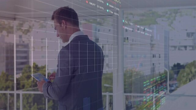 Executive tapping tablet by glass window analyzing market data and activating holographic graphs