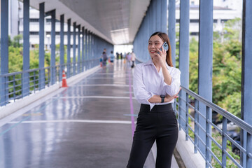 Fototapeta premium A woman is talking on her cell phone while standing on a bridge