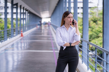 Fototapeta premium A woman is talking on her cell phone while standing on a bridge