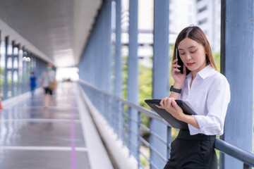 Fototapeta premium A woman is talking on her cell phone while looking at a tablet
