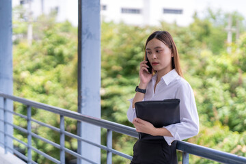 Fototapeta premium A woman is talking on her cell phone while holding a black purse