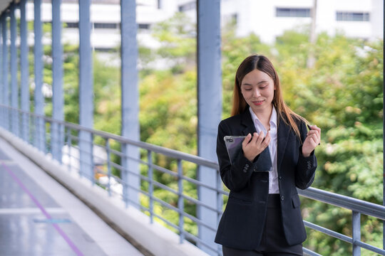 A woman in a business suit is looking at her tablet while standing on a balcony